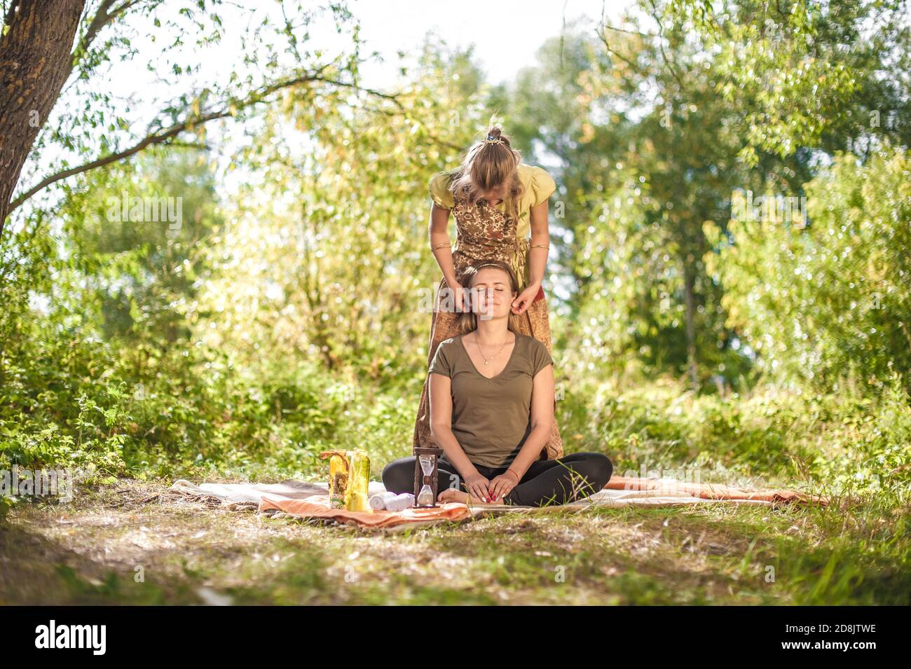 Une masseuse expérimentée donne à sa cliente un massage rafraîchissant dans la forêt. Banque D'Images