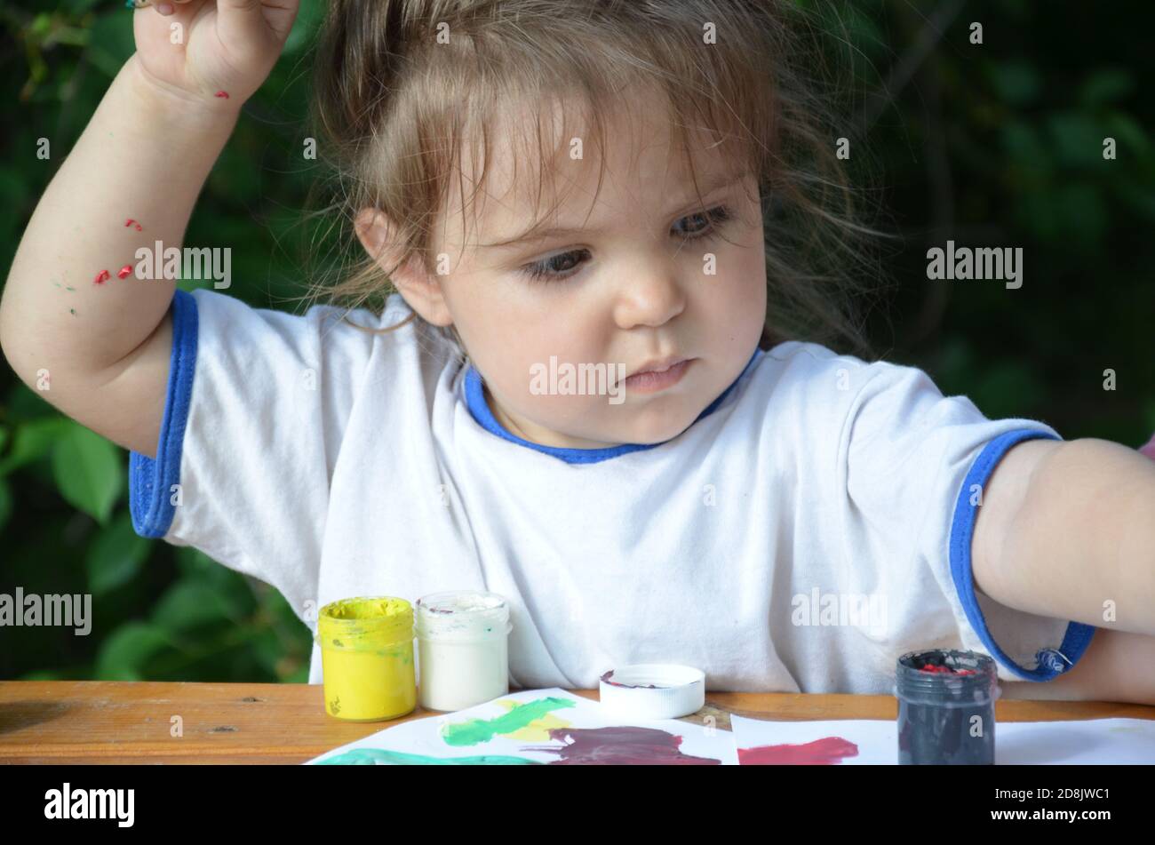 Une fille de 2 3 ans s'assoit à une table et dessine avec des peintures colorées. La créativité des enfants. Passe-temps pour les enfants. Banque D'Images