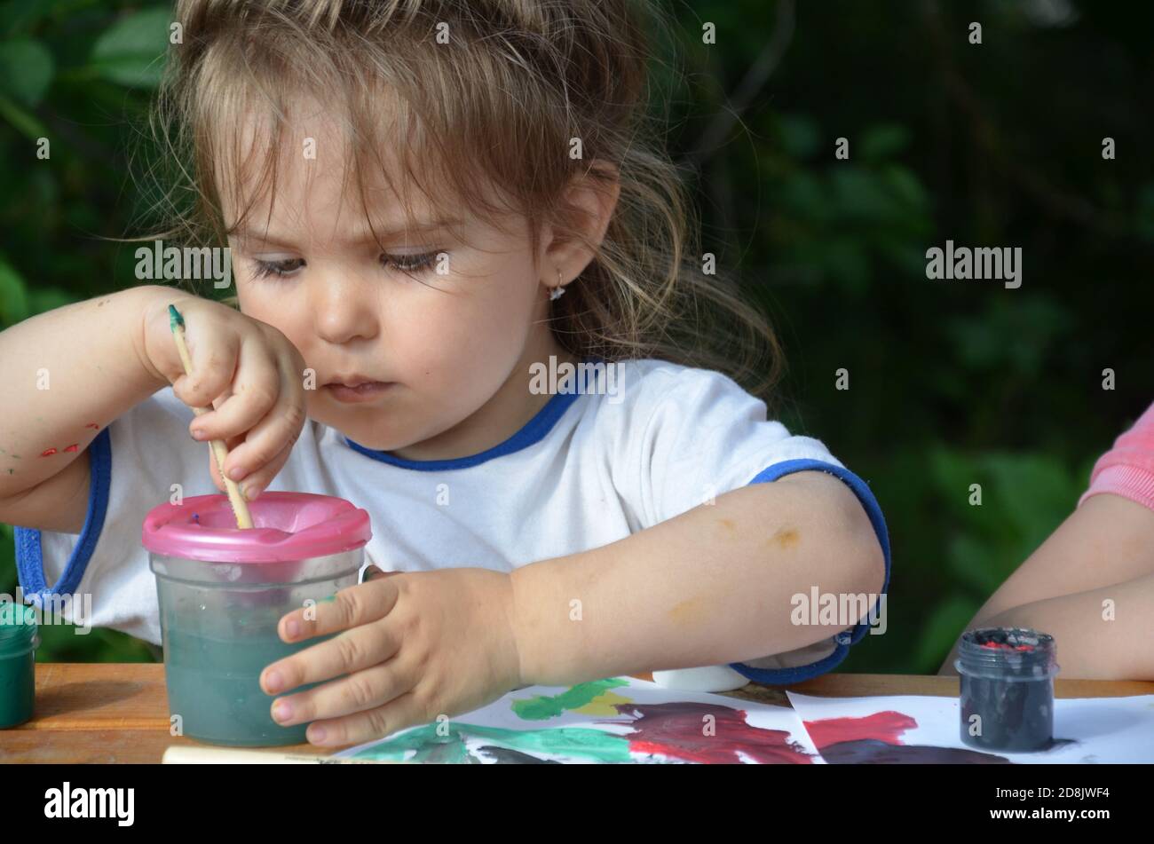 Une fille de 2 3 ans s'assoit à une table et dessine avec des peintures colorées. La créativité des enfants. Passe-temps pour les enfants. Banque D'Images