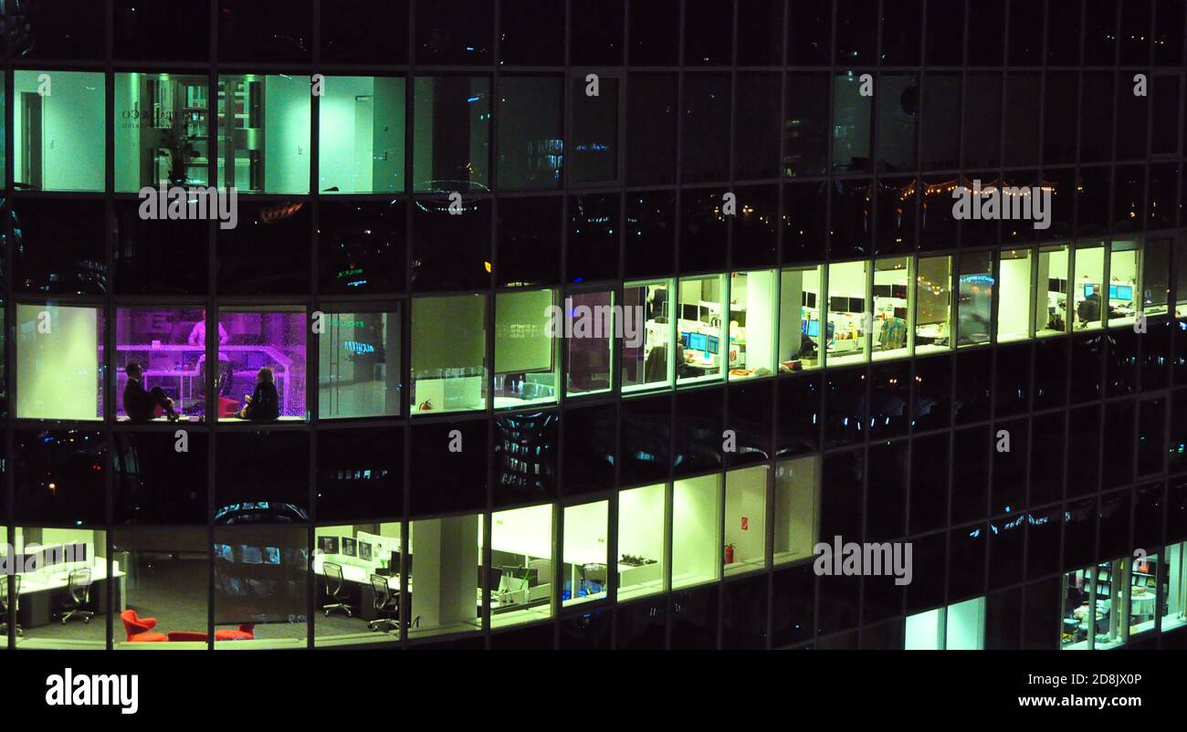 Vue nocturne d'un immeuble de bureaux et de bureaux vides, deux personnes assises près de la fenêtre violette, Francfort, Allemagne Banque D'Images Vue nocturne d'un immeuble de bureaux et de bureaux vides, deux personnes assises près de la fenêtre violette, Francfort, Allemagne Banque D'Images