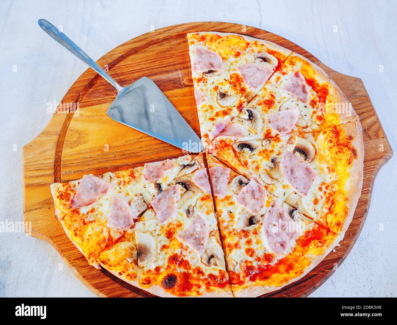 Pizza coupée en morceaux sur un plateau en bois avec un spatule métallique  Photo Stock - Alamy