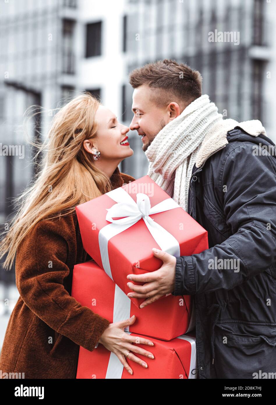 Couple d'amour échangeant des cadeaux à l'extérieur. Surprise romantique pour Noël. Grandes boîtes rouges cadeaux dans les mains Banque D'Images