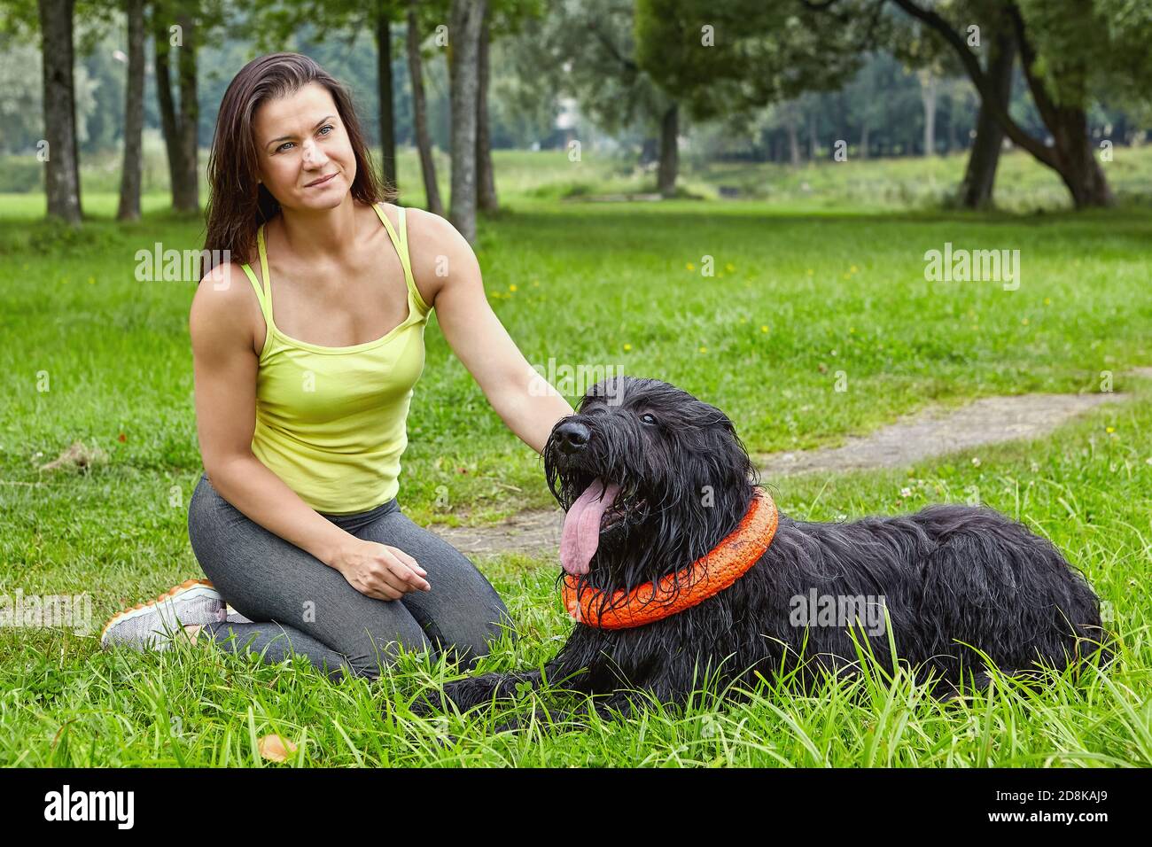Jeune femme pensive et briard noir pendant la marche dans le parc. Banque D'Images