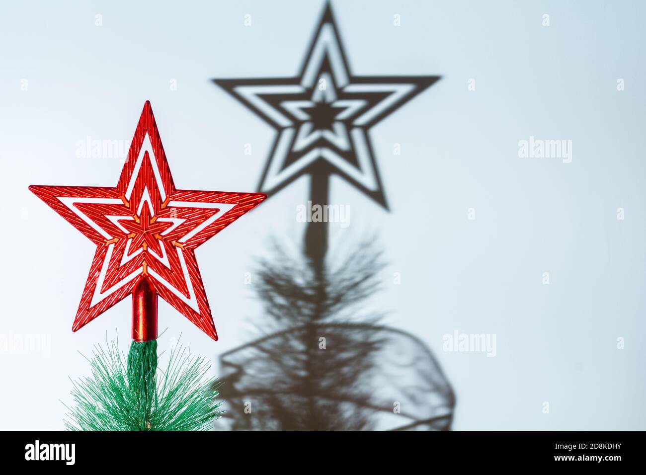 Gros plan d'une étoile rouge au-dessus d'un Noël arbre jetant une ombre sur le mur Banque D'Images