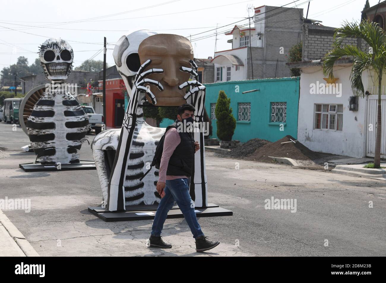 Mexico, Mexique. 30 octobre 2020. MEXICO, MEXIQUE - OCTOBRE 30 : une personne porte un masque facial lors de ses promenades devant un crâne monumental en carton, a été mise à décorer les rues de Tlahuac pour célébrer le jour des morts ( Dia de Muertos) dans le cadre de la pandémie de Covid-19. Le 30 octobre 2020 à Mexico, Mexique. Crédit: Ismael Rosas/Eyepix Group/The photo Access crédit: The photo Access/Alay Live News Banque D'Images