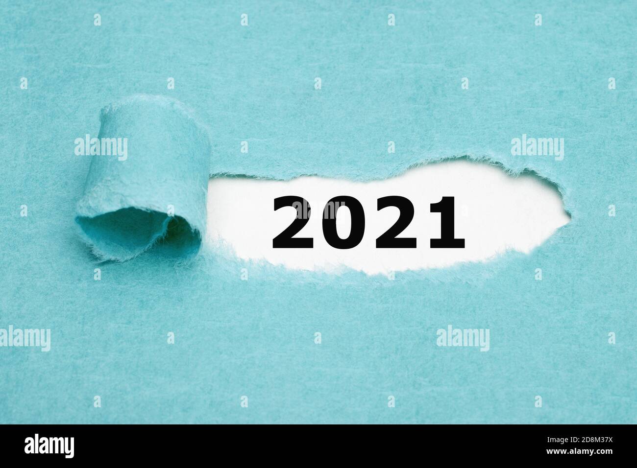 Les numéros imprimés 2021 apparaissent derrière du papier bleu déchiré. Concept de début d'année. Banque D'Images