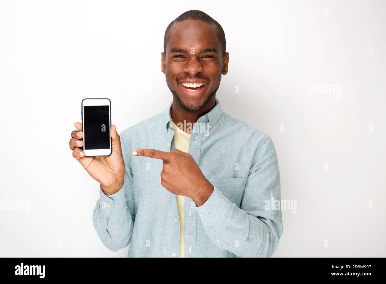 Portrait d'un jeune africain américain heureux tenant un téléphone portable et pointant vers l'écran Banque D'Images