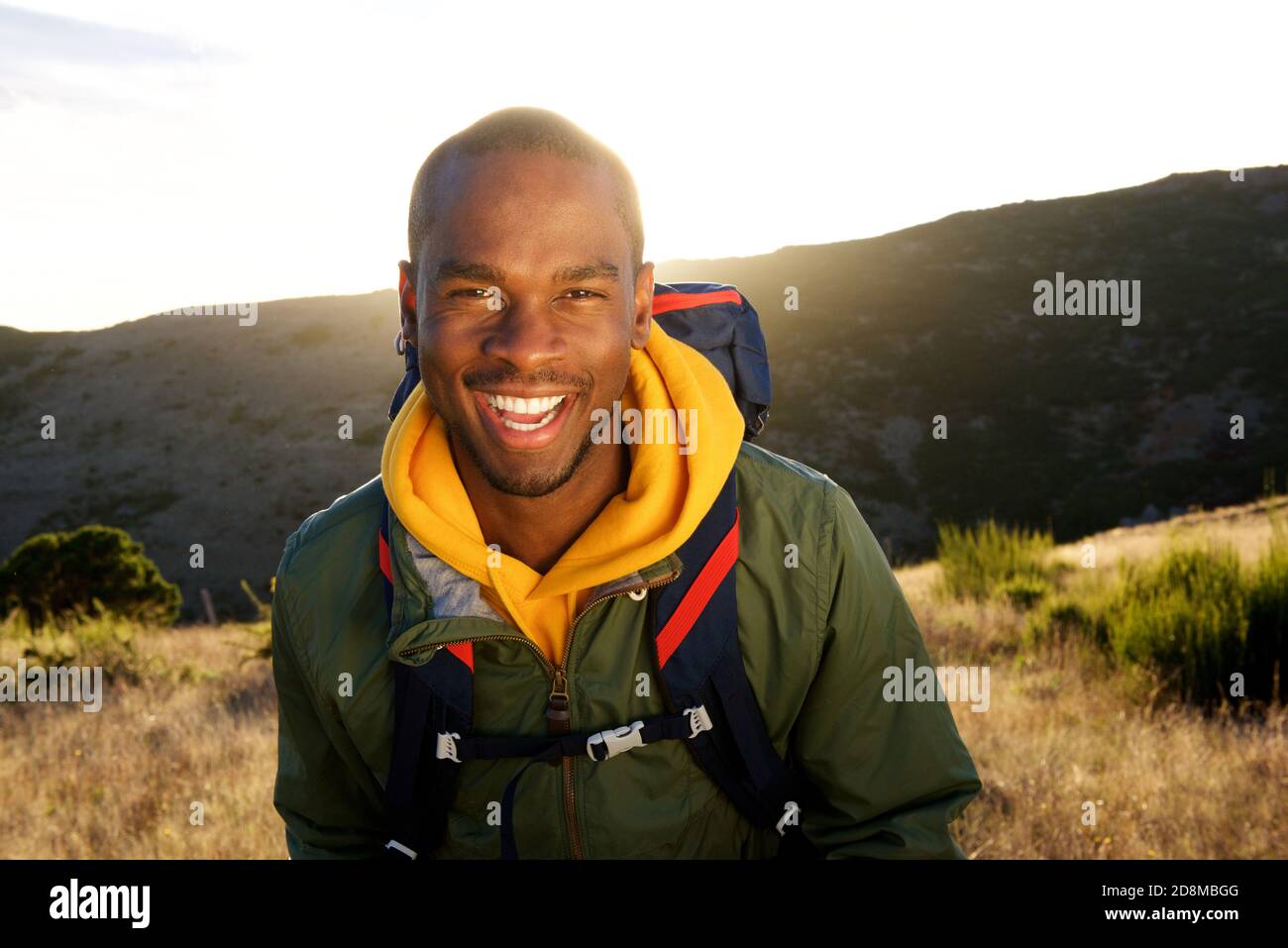 Portrait en gros plan d'un heureux africain américain qui marche à l'intérieur montagnes au lever du soleil Banque D'Images