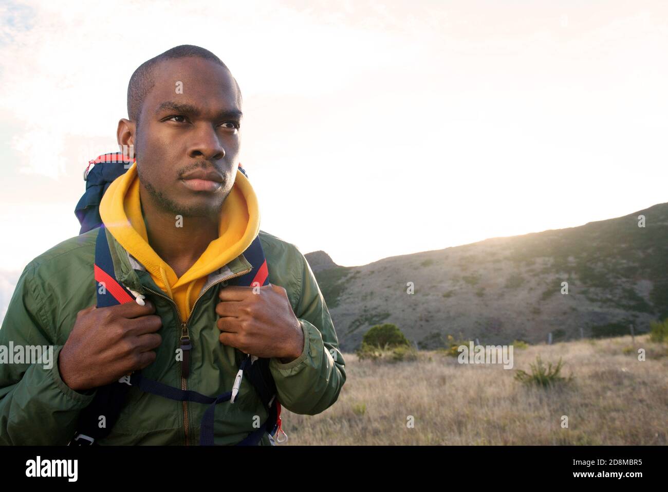 Portrait en gros plan d'un jeune homme noir marchant dans les montagnes avec sac à dos tôt le matin Banque D'Images