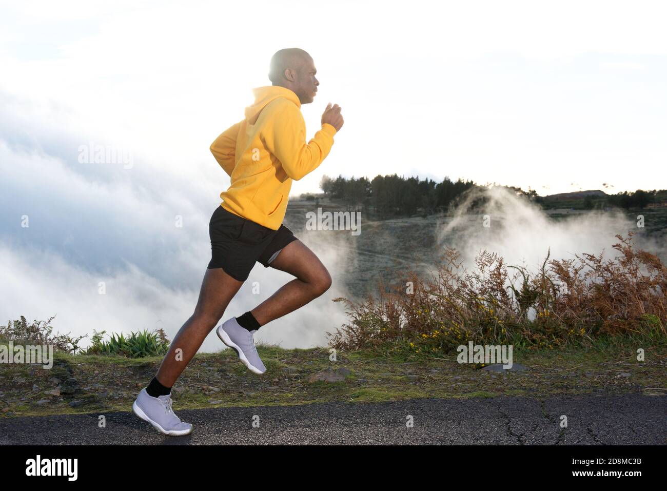 Portrait latéral complet du jeune homme noir en train de courir sur route dans la nature Banque D'Images