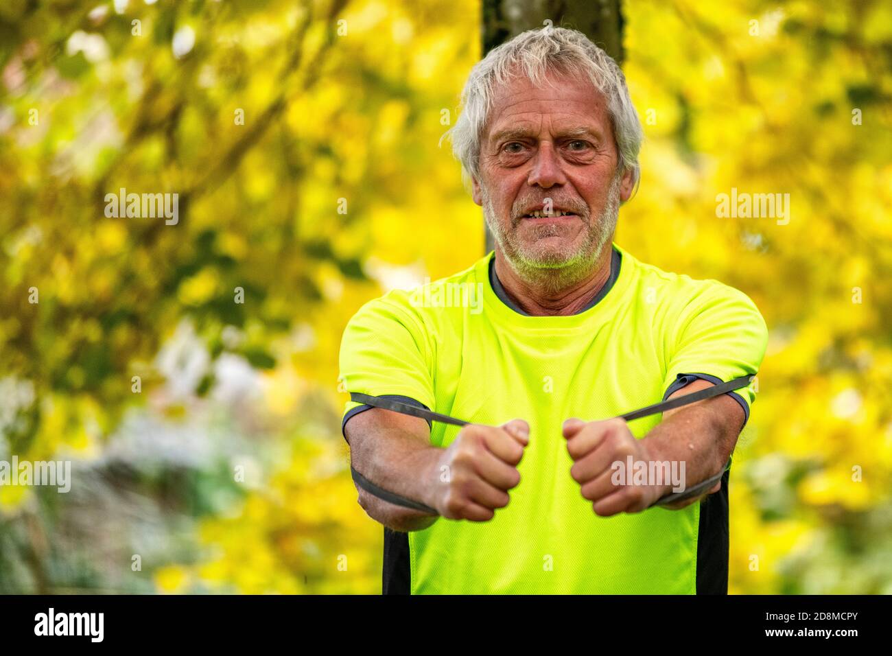 Un homme de la fin des années 60 s'exerce à l'extérieur avec un groupe de résistance en automne. Banque D'Images