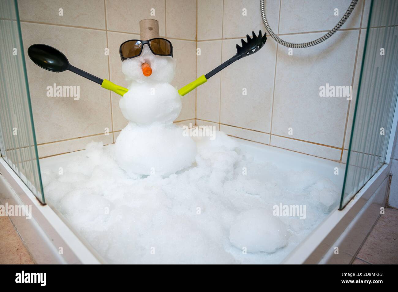 Petit bonhomme de neige construit à l'intérieur d'une douche avec des couverts pour les mains. Banque D'Images