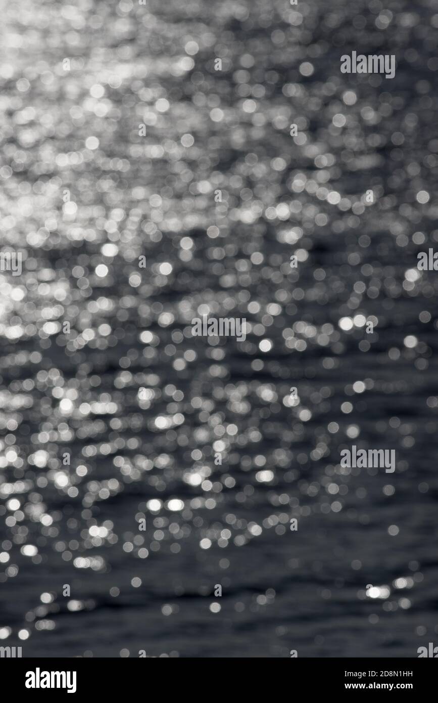 5 - image verticale défocuée des ondulations d'eau ensoleillées, formant un arrière-plan abstrait texturé de cercles de bokeh blancs aléatoires. Thème de l'eau. Banque D'Images