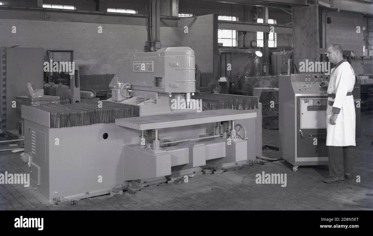 Années 1950, historique, un opérateur masculin debout par une unité de contrôle de la Bunker-Rand Corporation liée à une grande pièce de machines à bois fabriquées par Ekstrom-Carlson & Co de Rockford, ILL, USA, une société fondée en 1904. Banque D'Images
