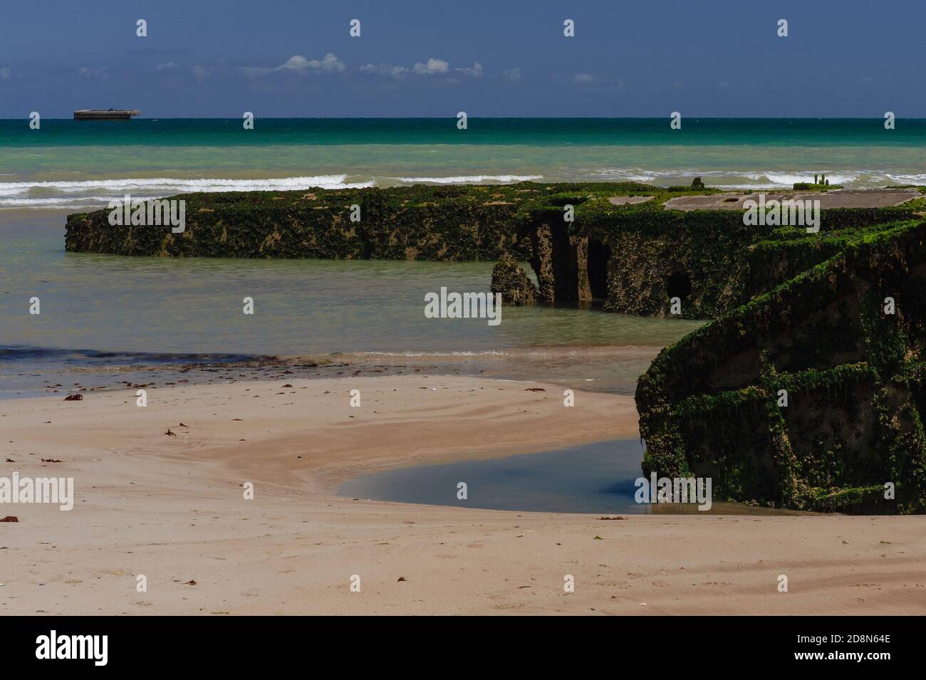 Les algues et les barnacles s'accrochent aux reliques de la Seconde Guerre mondiale 1944 débarquement allié, accessible à pied seulement à marée basse sur la plage d'Or à Arromanches-les-bains, Calvados, Normandie, France. Certains caissons en béton précoulé ou des sections creuses de Port Winston ou de Mulberry Harbour B se trouvent sur la plage, tandis que d'autres vestiges survivent plus loin en mer. La vaste structure était l'un des deux ports portables préfabriqués tractés à travers la Manche pour aider à l'invasion de l'Europe occupée par les nazis. Il a été utilisé après le jour J pour atterrir des millions de troupes, de véhicules et de fournitures. Banque D'Images