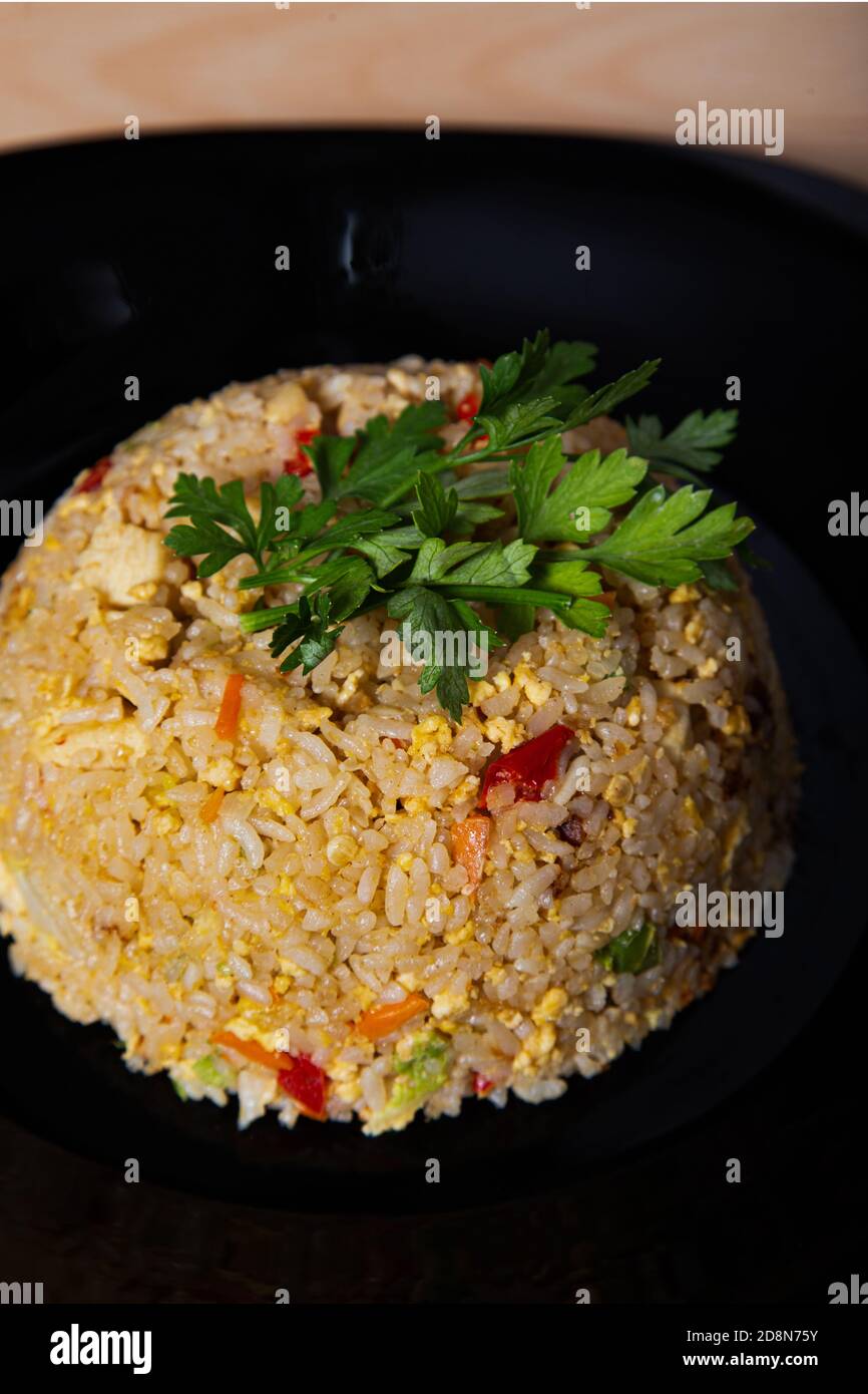 Dose verticale de délicieux riz sauté avec poulet et légumes sur une plaque sur la table Banque D'Images