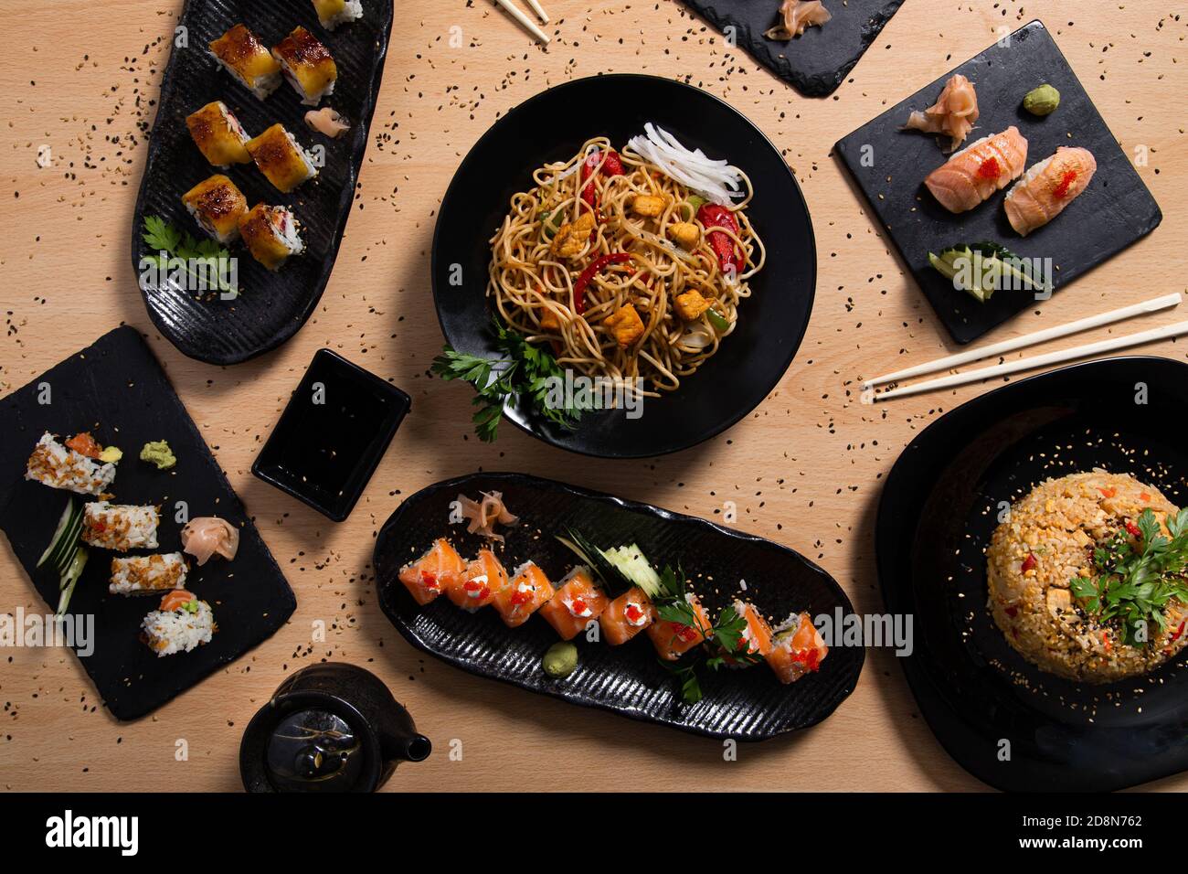 Variété de sushis avec riz sauté et poulet et légumes, et un bol de nouilles sur la table Banque D'Images