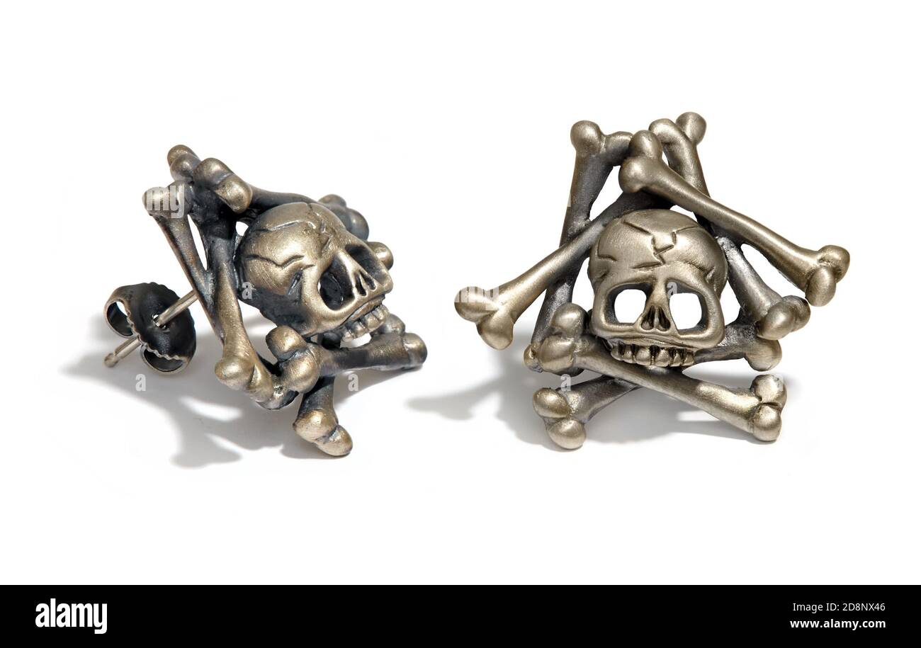 Paire de boucles d'oreilles en forme de crâne et d'os croisés argentés et dorés Conçu par Wendy Brandes photographié sur fond blanc Banque D'Images