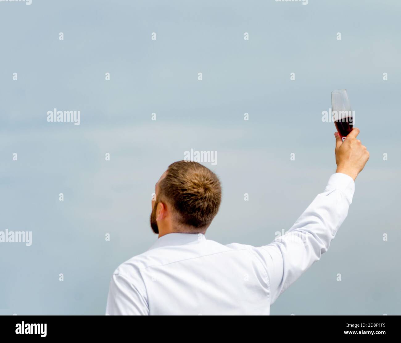 employé de bureau dans une chemise blanche avec un verre de vin dans une main levée Banque D'Images