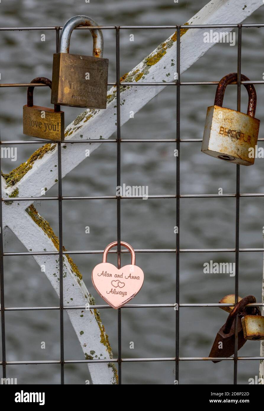 cadenas enchaînés à une clôture et quelques chemins de fer sur un pont au-dessus de la rivière dans le parc thermal leamington royaume-uni, keepsakes et souvenirs des amoureux sur une clôture. Banque D'Images