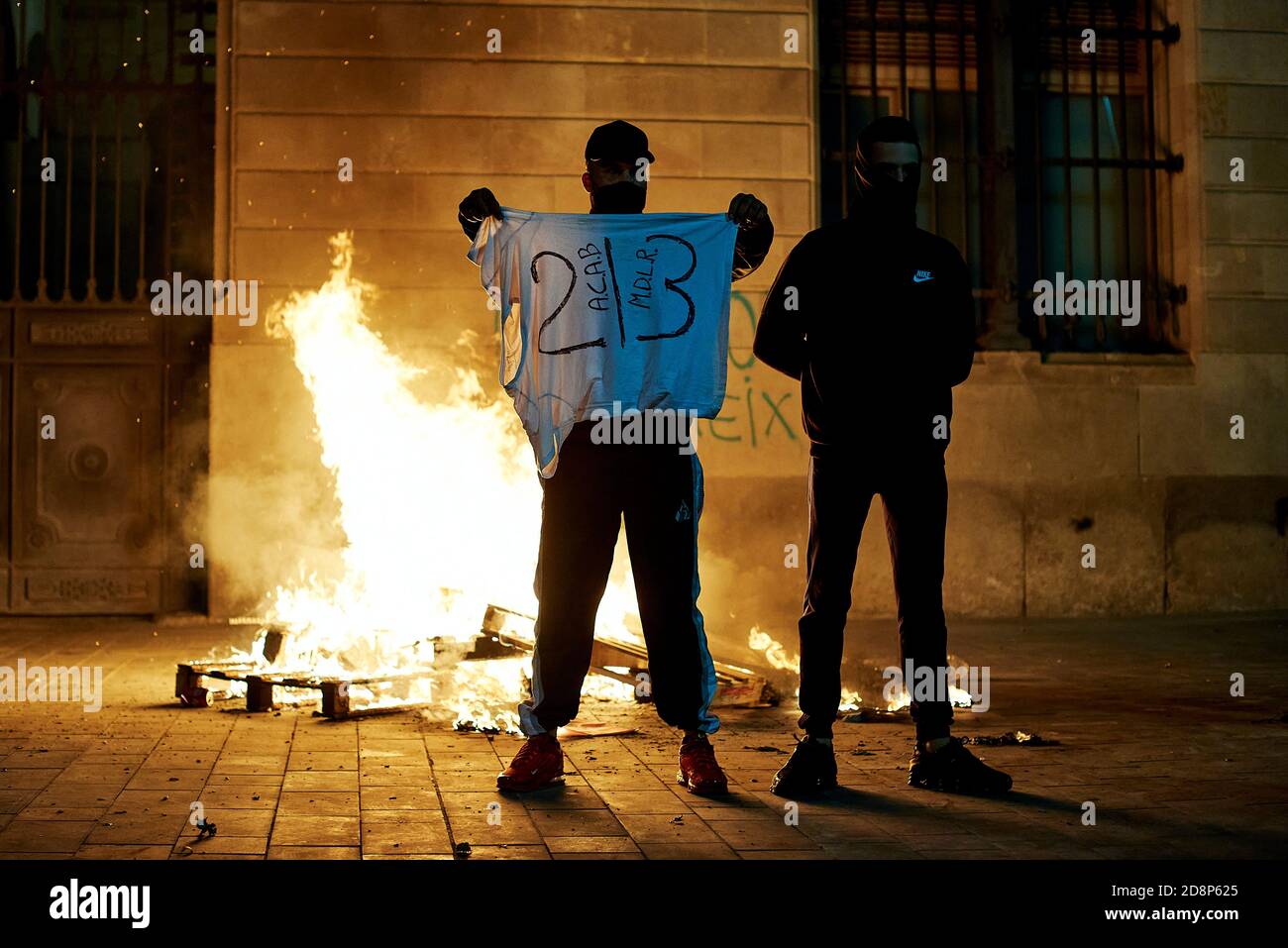 Barcelone, Catalunya, España 31 octobre 2020. BARCELONE, ESPAGNE - OCTOBRE 31 : deux manifestants devant un feu de camp avec les initiales A.C.A.B, M.D.L.R et le numéro 213. Lors de la manifestation contre les expulsions qui ont eu lieu la semaine dernière à Barcelone et l'expulsion de Casa Buenos Aires. 31 octobre 2020 à Barcelone, Espagne. Credit: Miguel Lopez Mallch/DAX/ZUMA Wire/Alamy Live News Banque D'Images