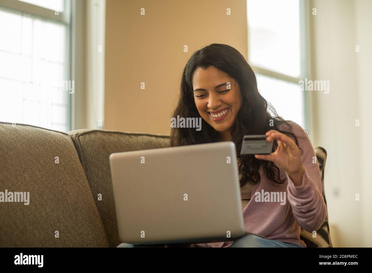 Young Hispanic woman shopping online à la maison. Banque D'Images