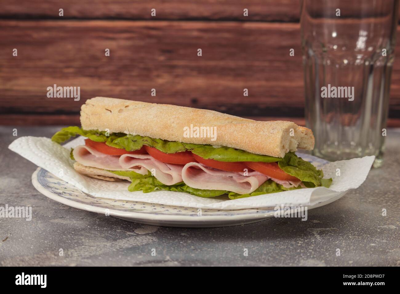 Sandwich au jambon, à la tomate et à la laitue sur une plaque de plaque sur un fond rustique Banque D'Images