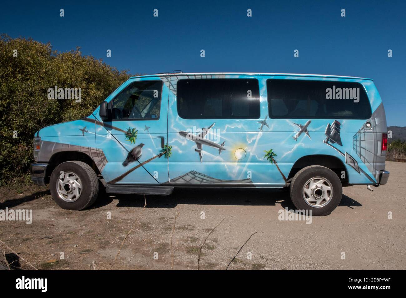 Une camionnette peint avec des avions, des palmiers et des oiseaux garés dans un lot vide. Banque D'Images