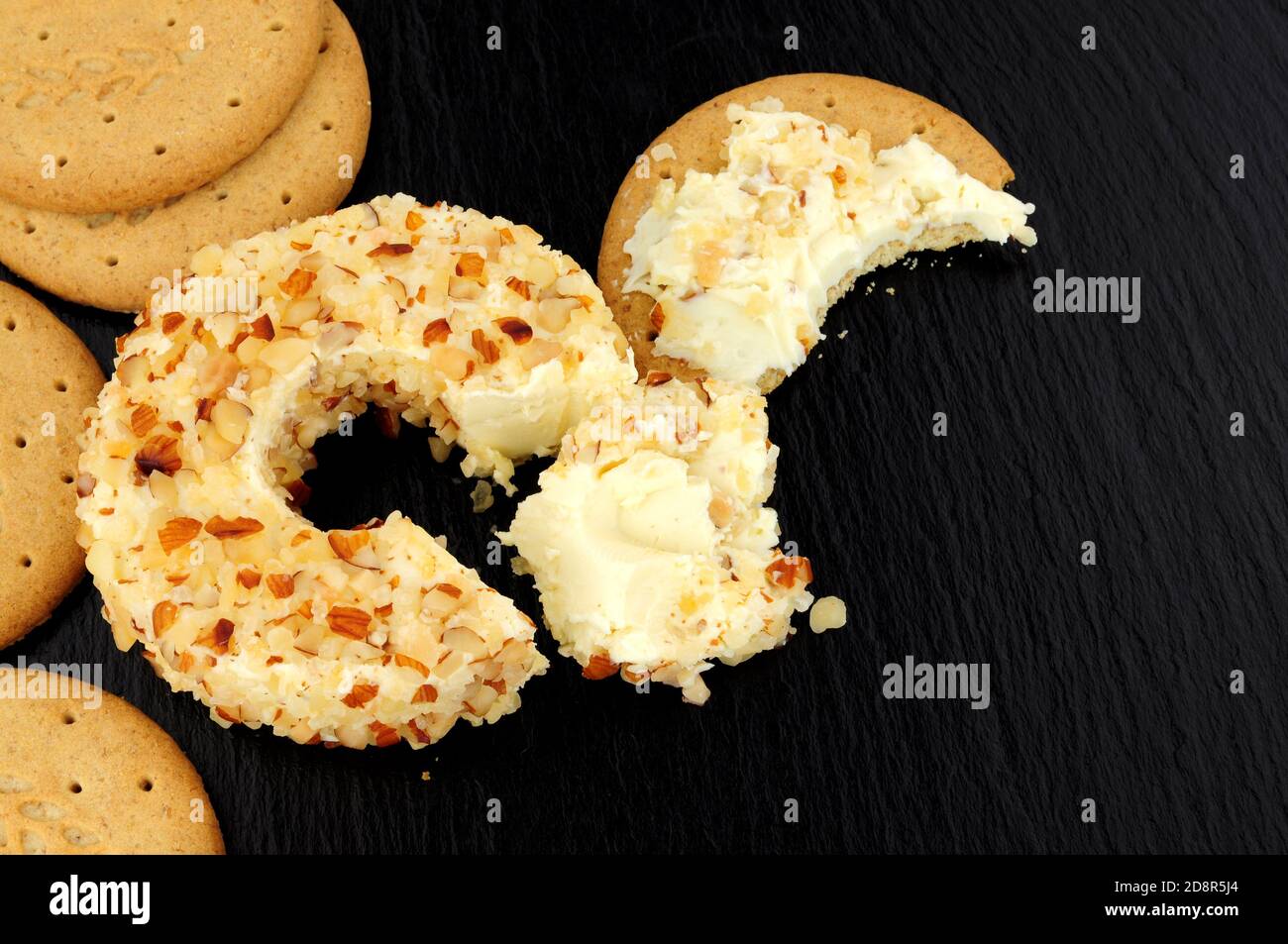Anneau de fromage à la crème douce au goût de l'ananas enrobé d'amandes écrasées sur fond de pierre d'ardoise Banque D'Images