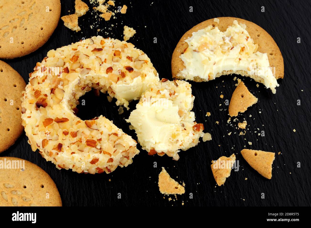 Anneau de fromage à la crème douce au goût de l'ananas enrobé d'amandes écrasées sur fond de pierre d'ardoise Banque D'Images