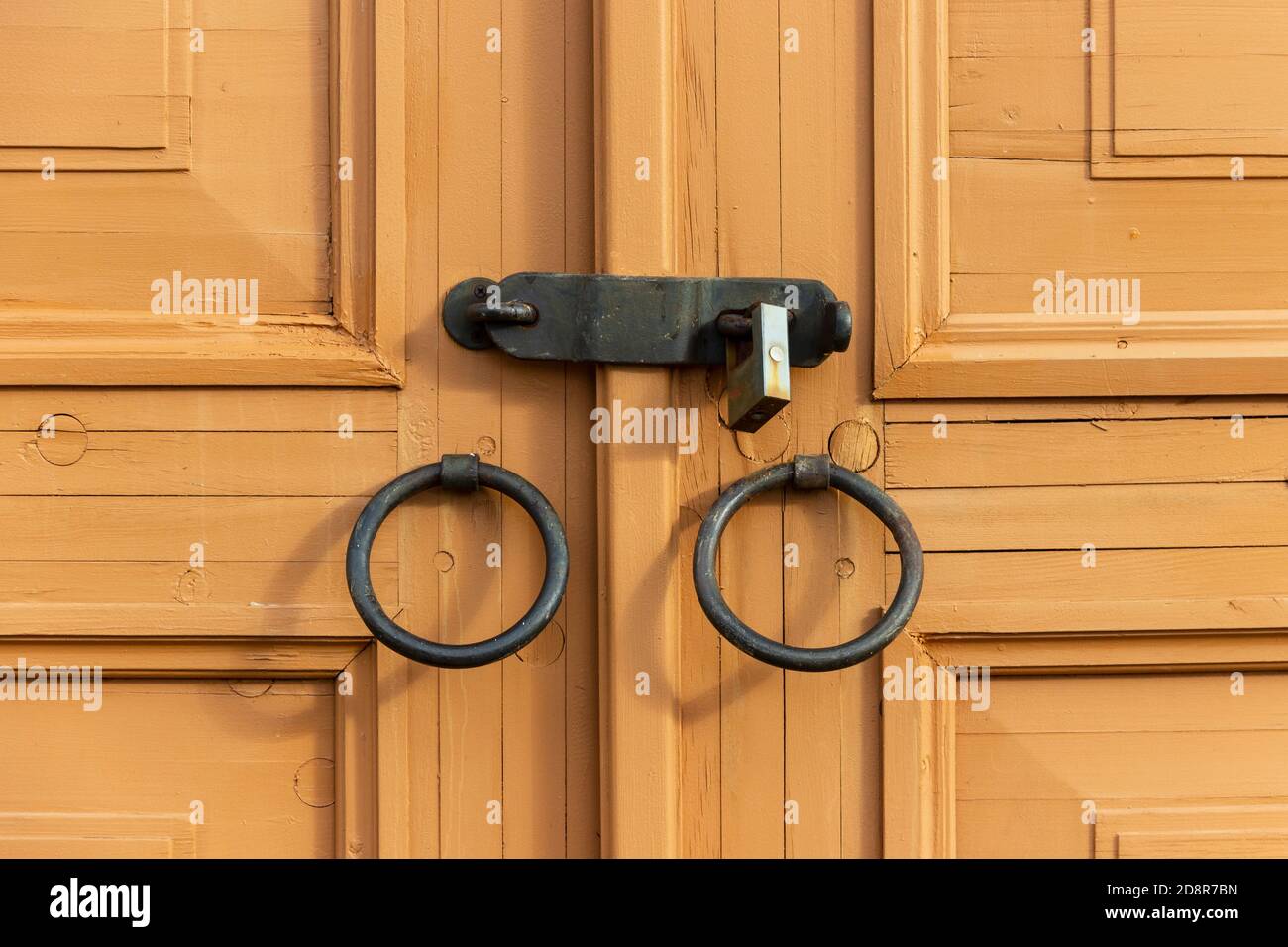 Porte en bois avec poignées en fer forgé, fermée par un boulon en acier avec une serrure. Banque D'Images