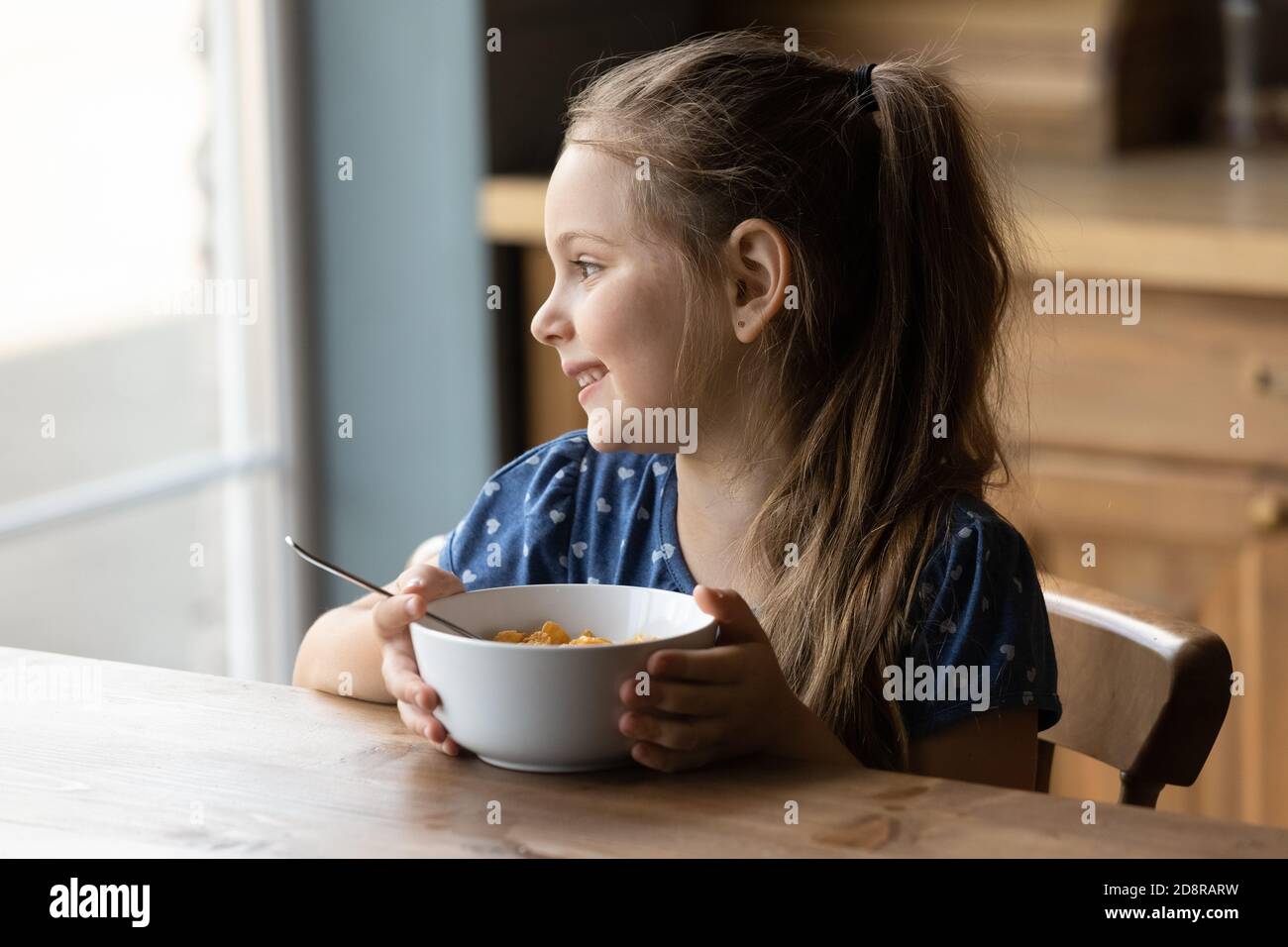 Une petite fille souriante prend un petit déjeuner sain à la maison Banque D'Images