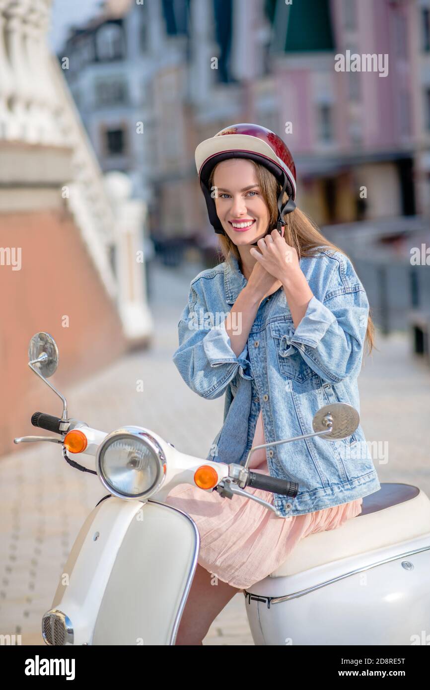 Femme portant une veste en denim et un casque rouge Banque D'Images