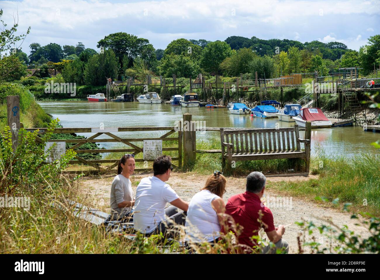 Deux couples s'assoient le long de la rivière des marées Arun lors d'une chaude journée d'été en juillet - Arundel, West Sussex, Angleterre, Royaume-Uni Banque D'Images