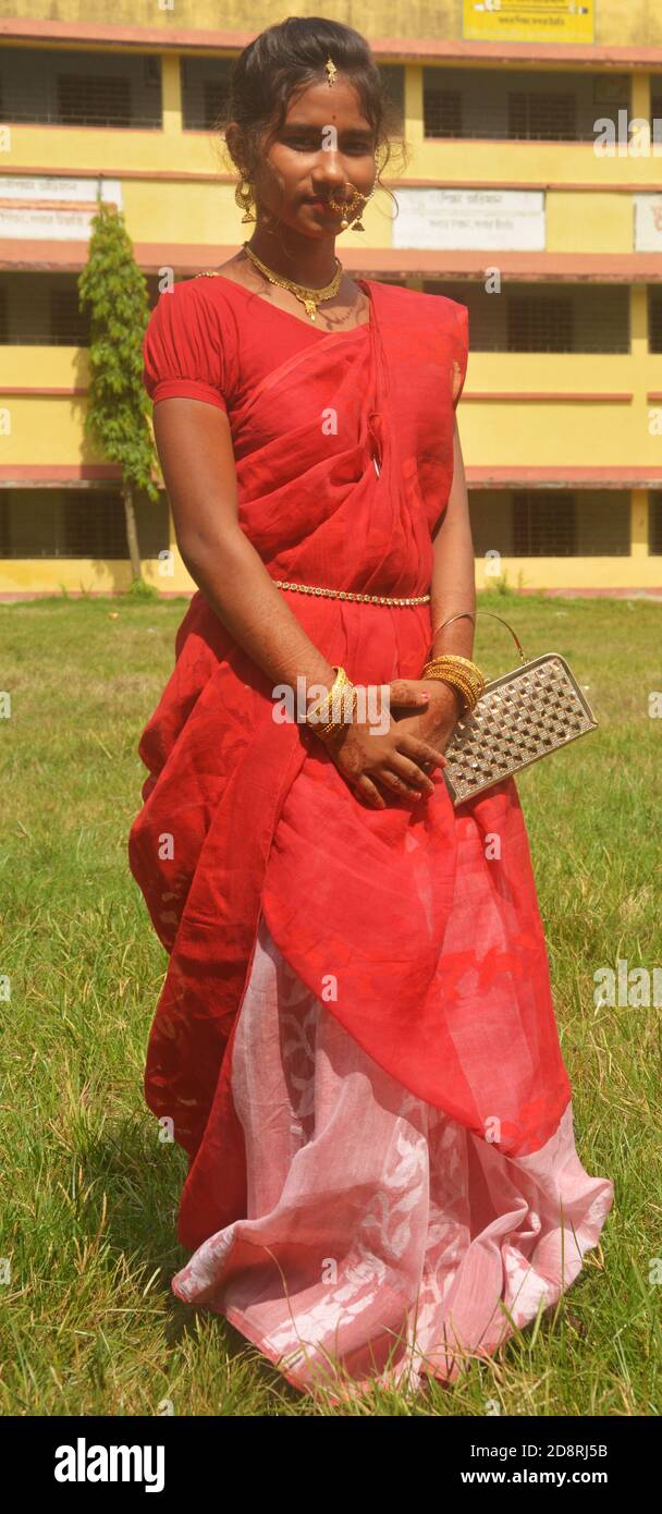 Gros plan d'une adolescente bengali indienne avec de longs poils foncés portant un sari rouge traditionnel avec des bracelets sac à main et un anneau de nez de bijouterie, boucle d'oreille. Banque D'Images