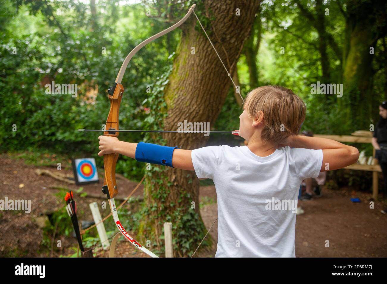 Un garçon visant une flèche à une cible Banque D'Images