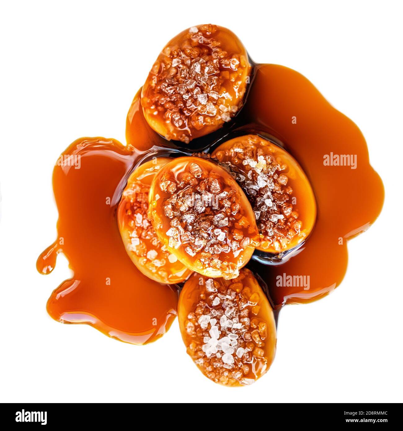 Sucreries sucrées avec garniture au caramel salé isolées sur fond blanc. Toffee avec sauce caramel gros plan. Vue de dessus. Banque D'Images