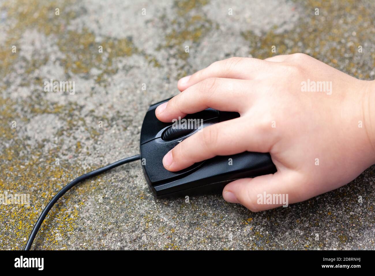 Petit enfant main sur une souris d'ordinateur, gros plan. Enfant en appuyant sur un bouton maintenant une souris PC noire de près, vue du dessus. Jeunes enfants sur Internet Banque D'Images