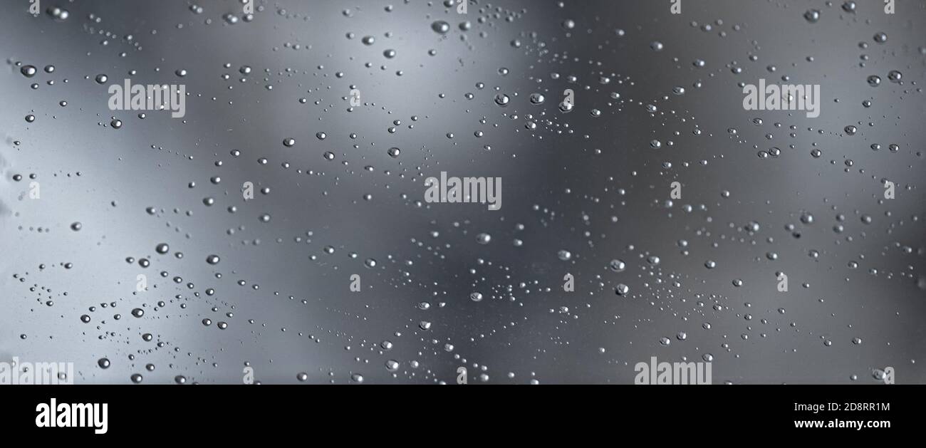 L'eau de pluie tombe sur une vitre noire spectaculaire. Arrière-plan de dépression de bokeh d'automne. Motif pluie Banque D'Images