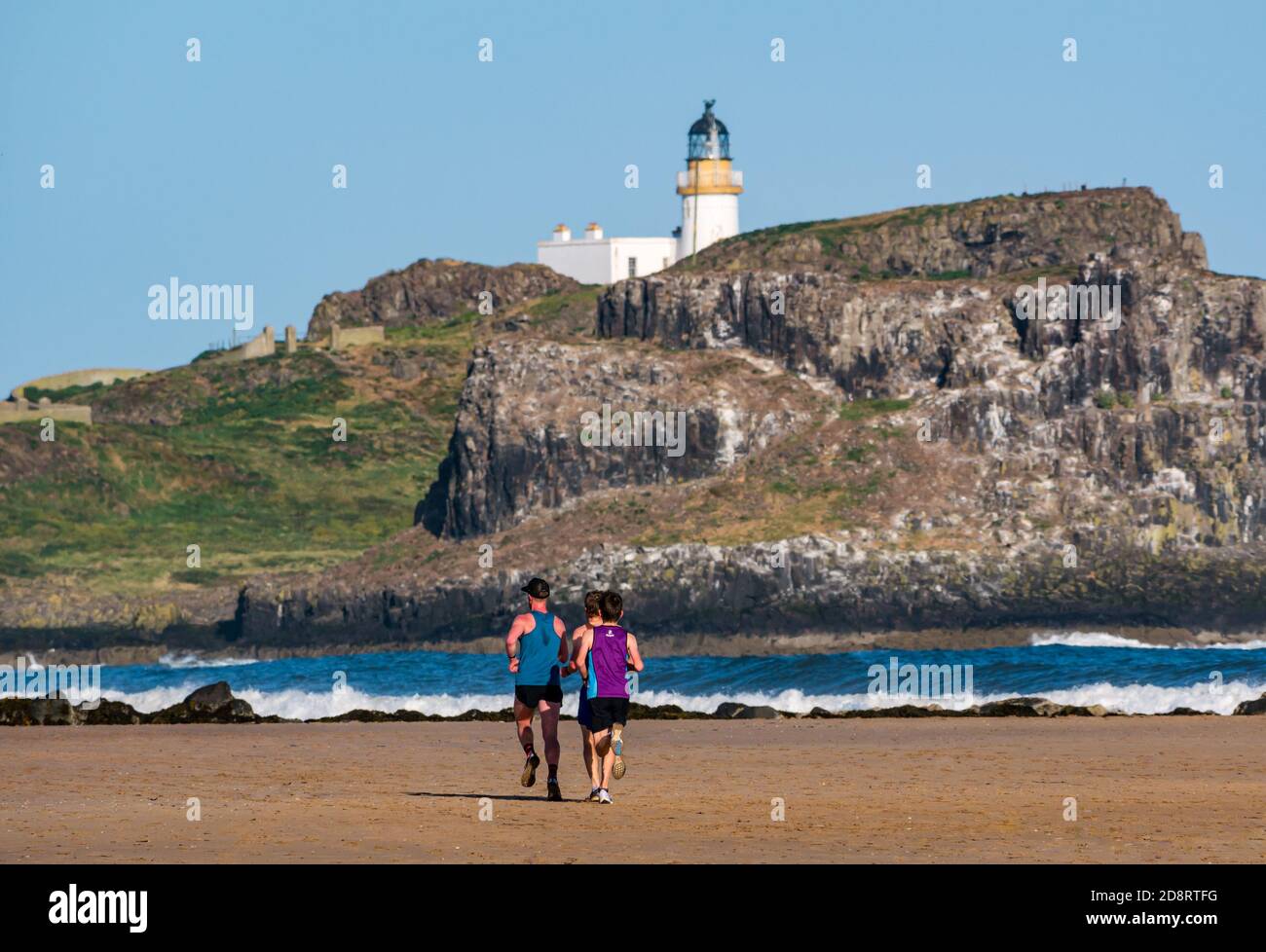 Courses de course à pied, plage de Yellowcraig avec Fidra Island & phare, East Lothian, Écosse, Royaume-Uni Banque D'Images