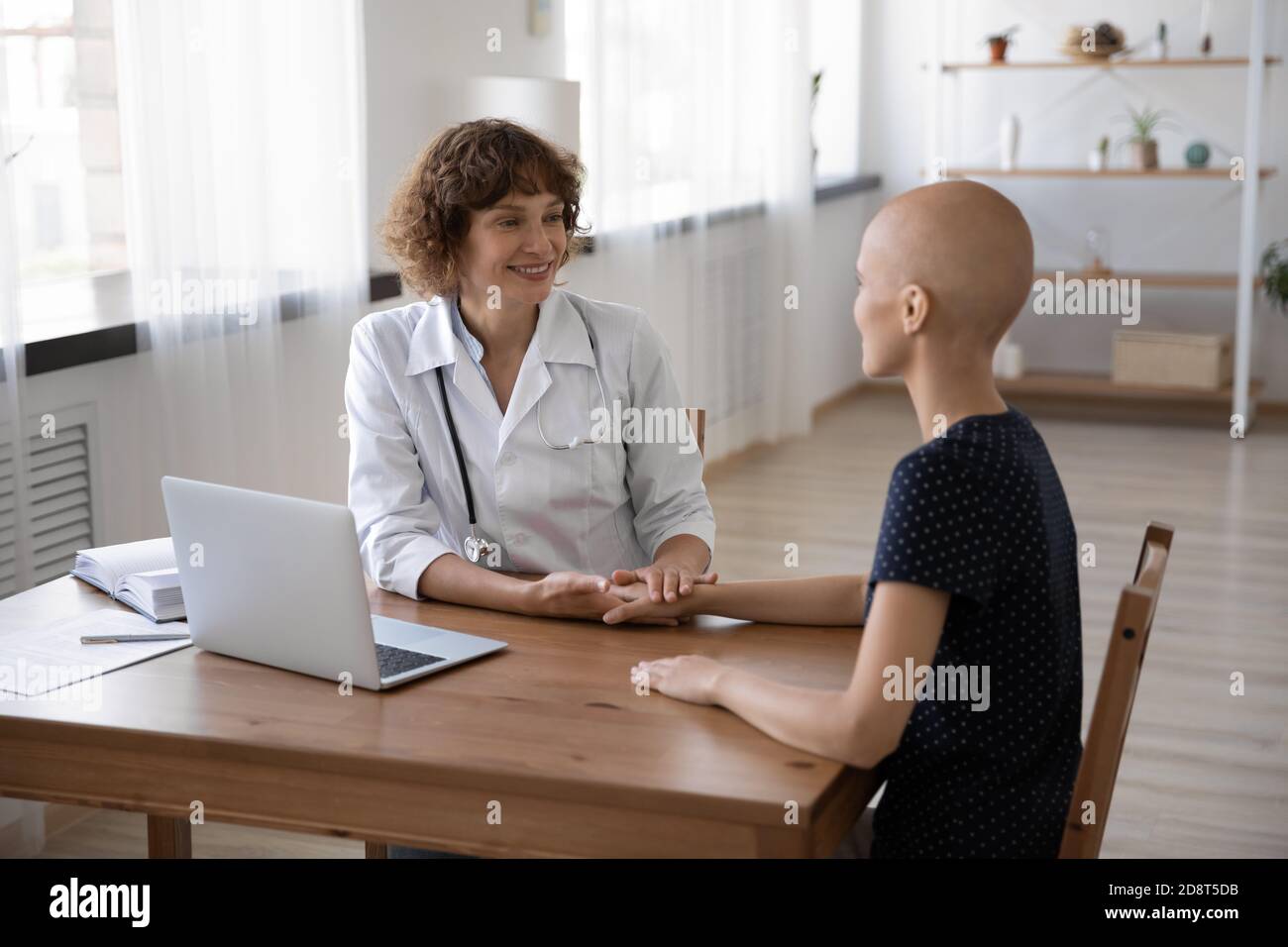 Médecin soignant tenant la main d'une femme sans cheveux pendant un rendez-vous médical Banque D'Images
