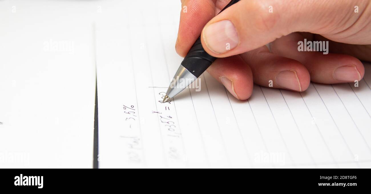 L'étudiant résout les formules mathématiques. L'homme écrit avec un stylo dans un bloc-notes. Devoirs. Notes dans un bloc-notes. Banque D'Images