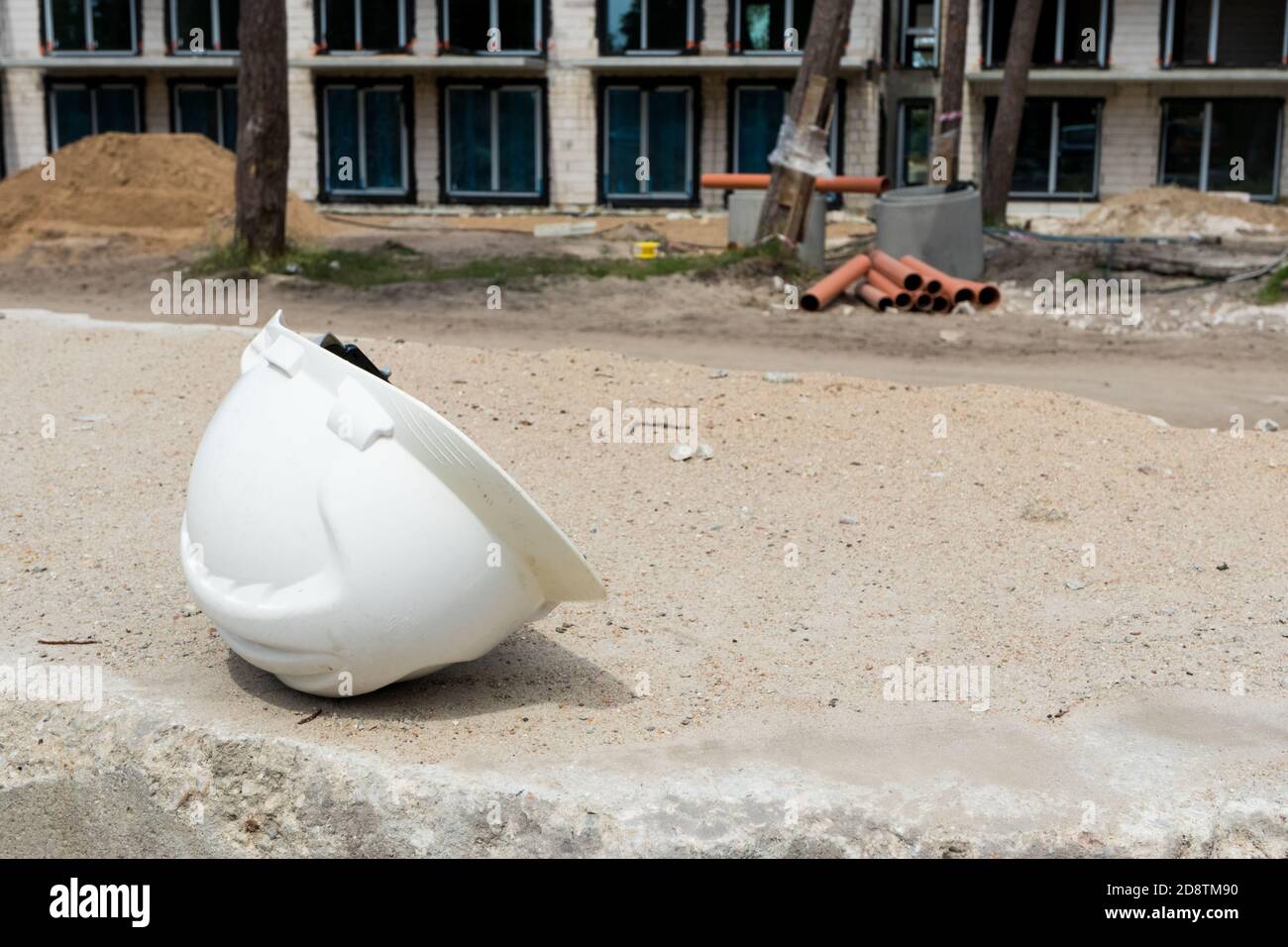 casque de construction couché sur une dalle de béton, site de construction en arrière-plan Banque D'Images
