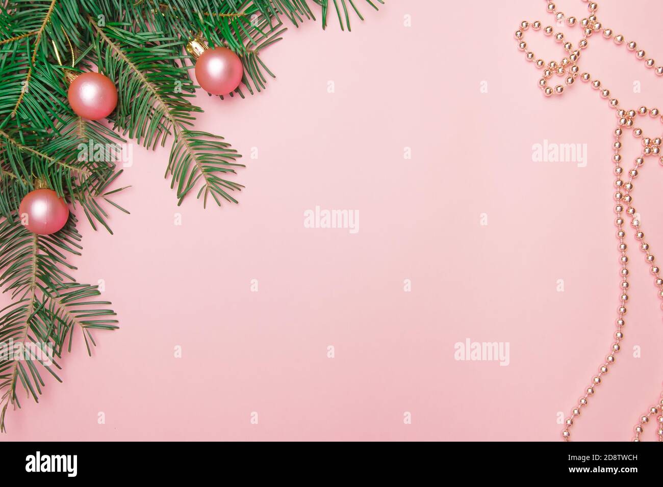 Fond rose de Noël avec branche de sapin, boules roses et perles dans le coin avec espace de copie. Banque D'Images