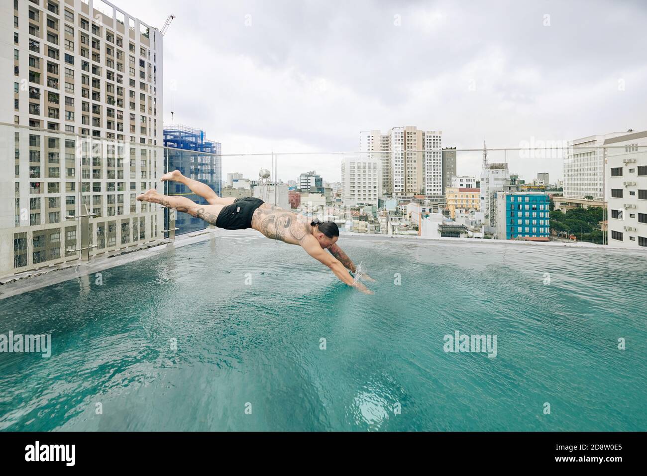 Homme sautant dans la piscine sur le toit Banque D'Images