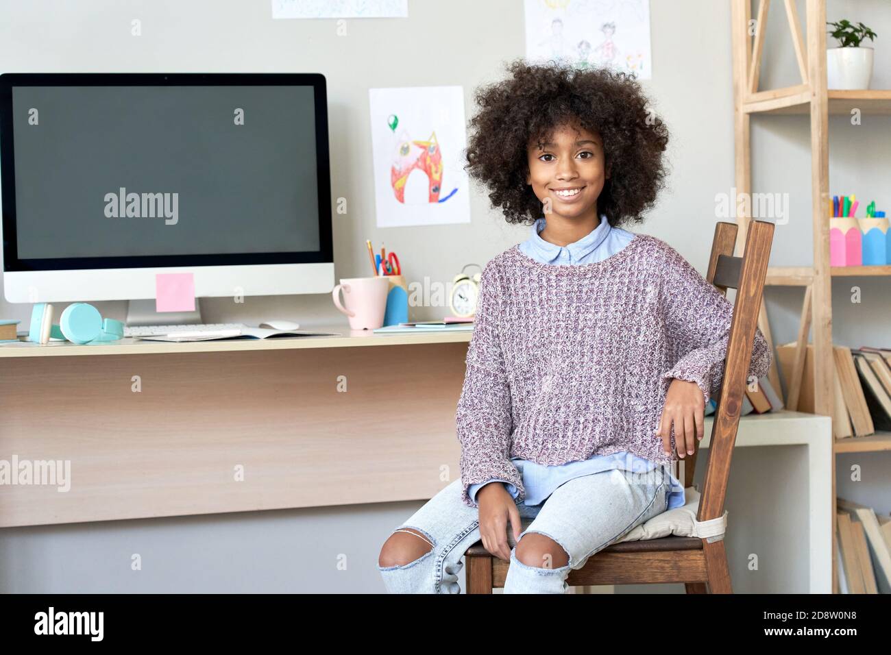 Bonne fille africaine regardant l'appareil photo assis à la maison bureau avec ordinateur. Banque D'Images
