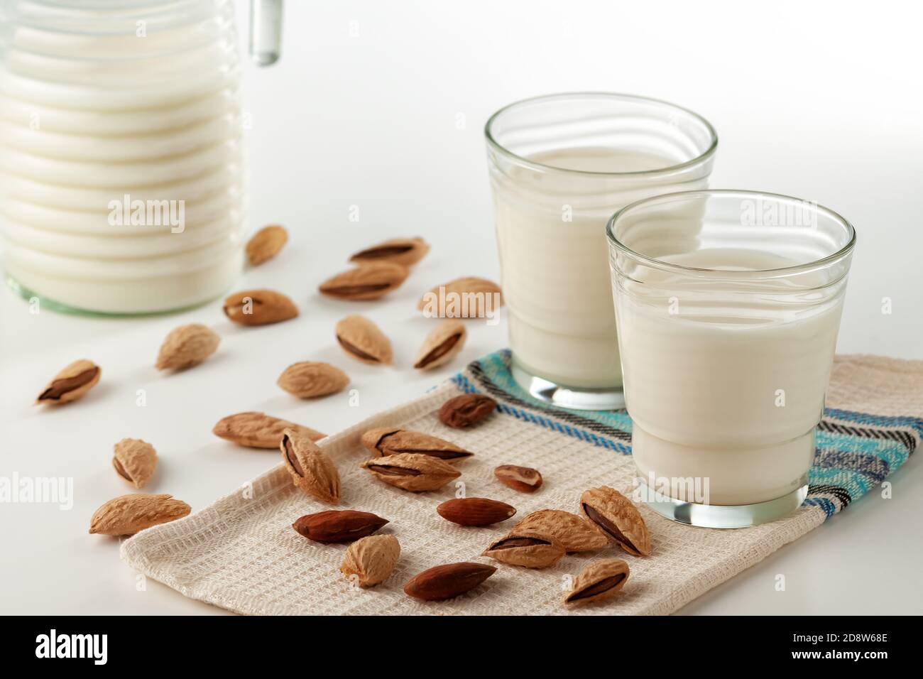 Lait d'amande dans un verre avec des amandes sur un blanc tableau Banque D'Images