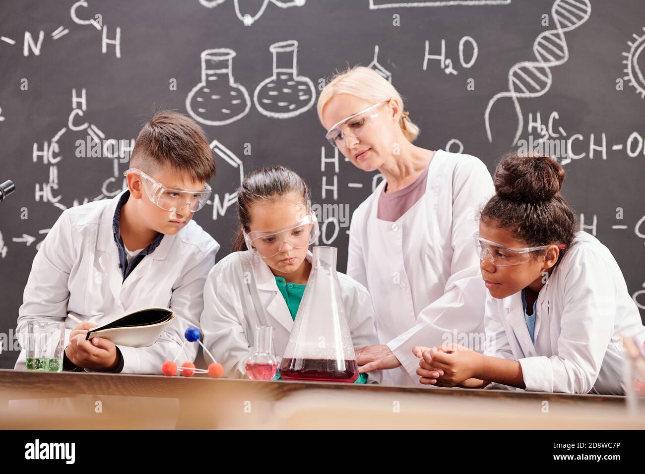 Plusieurs élèves de l'école secondaire et enseignant faisant des expériences chimiques Banque D'Images