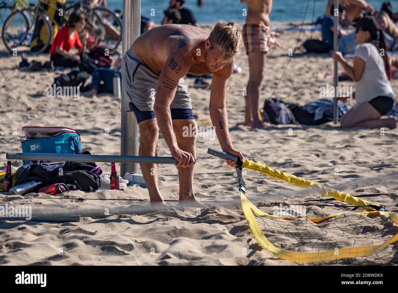 Un homme est vu démanteler le filet de volley-ball après avoir été informé par les policiers que la pratique du sport de groupe est interdite en raison de l'augmentation des infections à Covid19.la deuxième vague d'infections à Covid19 a causé des limites de périmètre par les municipalités et les provinces de Catalogne. Les parcs publics, les musées et les plages sont aujourd'hui les seuls espaces ouverts où passer du temps libre. Malgré cela, la Garde urbaine de Barcelone a dû intervenir pour interdire le volley-ball sur les plages. Seule la pratique du sport individuel est autorisée. Banque D'Images