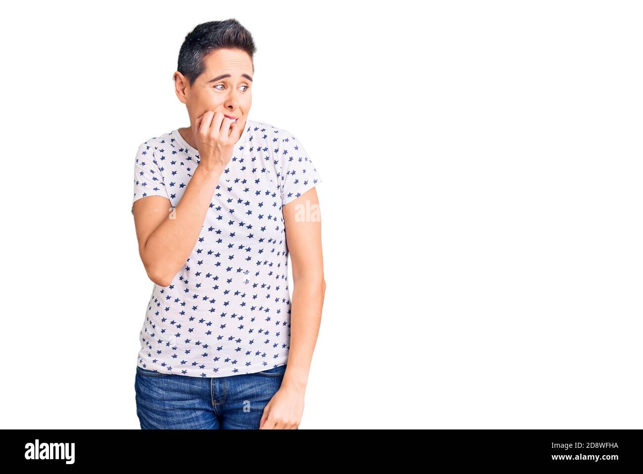 Jeune femme avec des cheveux courts portant des vêtements décontractés ayant l'air stressé et nerveux avec les mains sur la bouche piquant les ongles. Problème d'anxiété. Banque D'Images